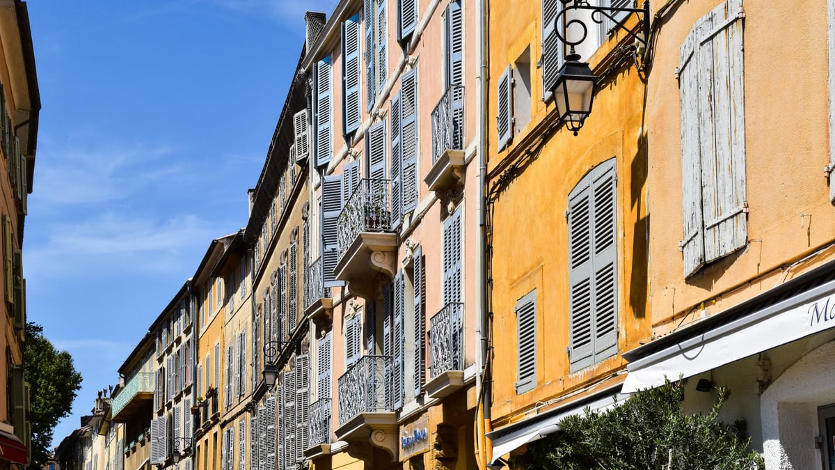 Colorful historic buildings on a sunny street in Aix-en-Provence, showcasing French architecture.